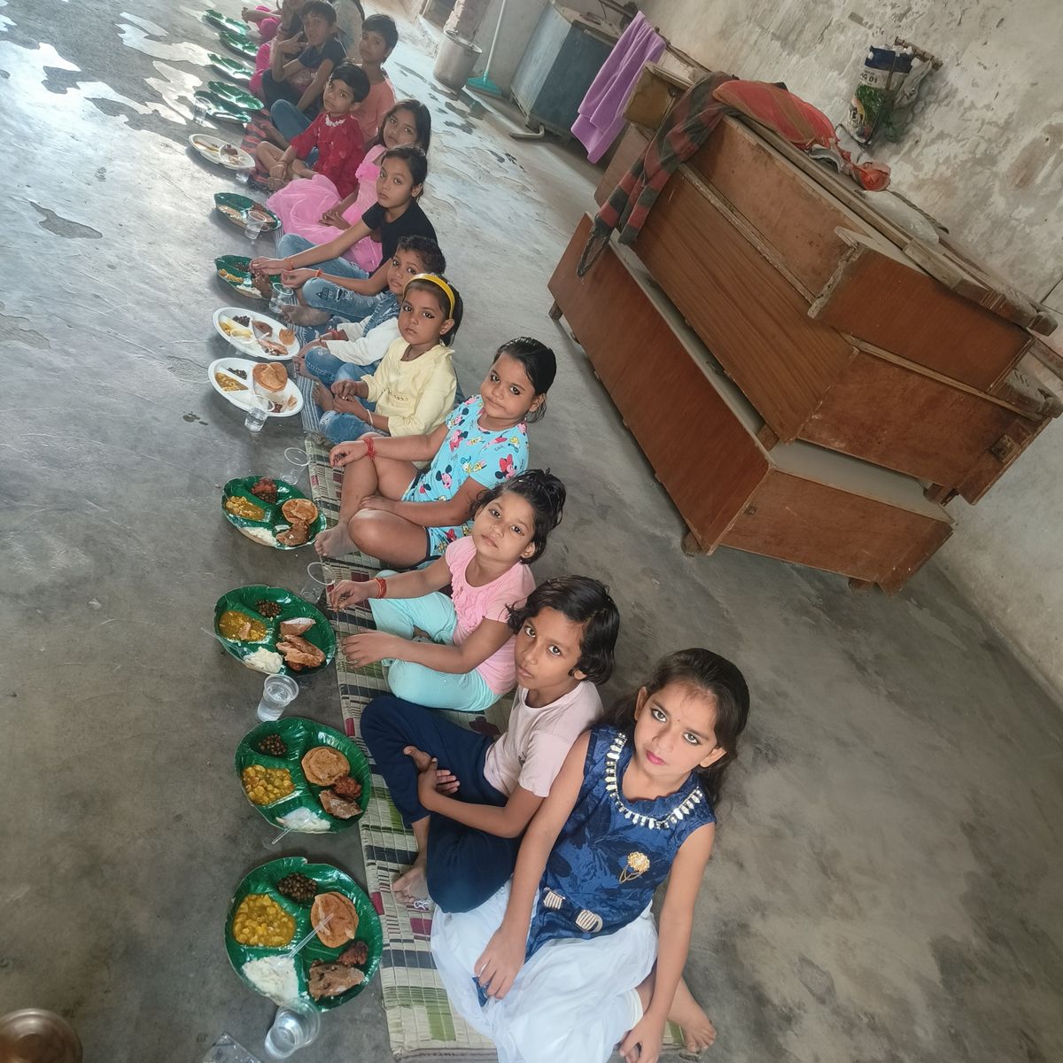 Young girls seated in a row for Kanya Pujan bhojan at Shiv Parmarth Dham